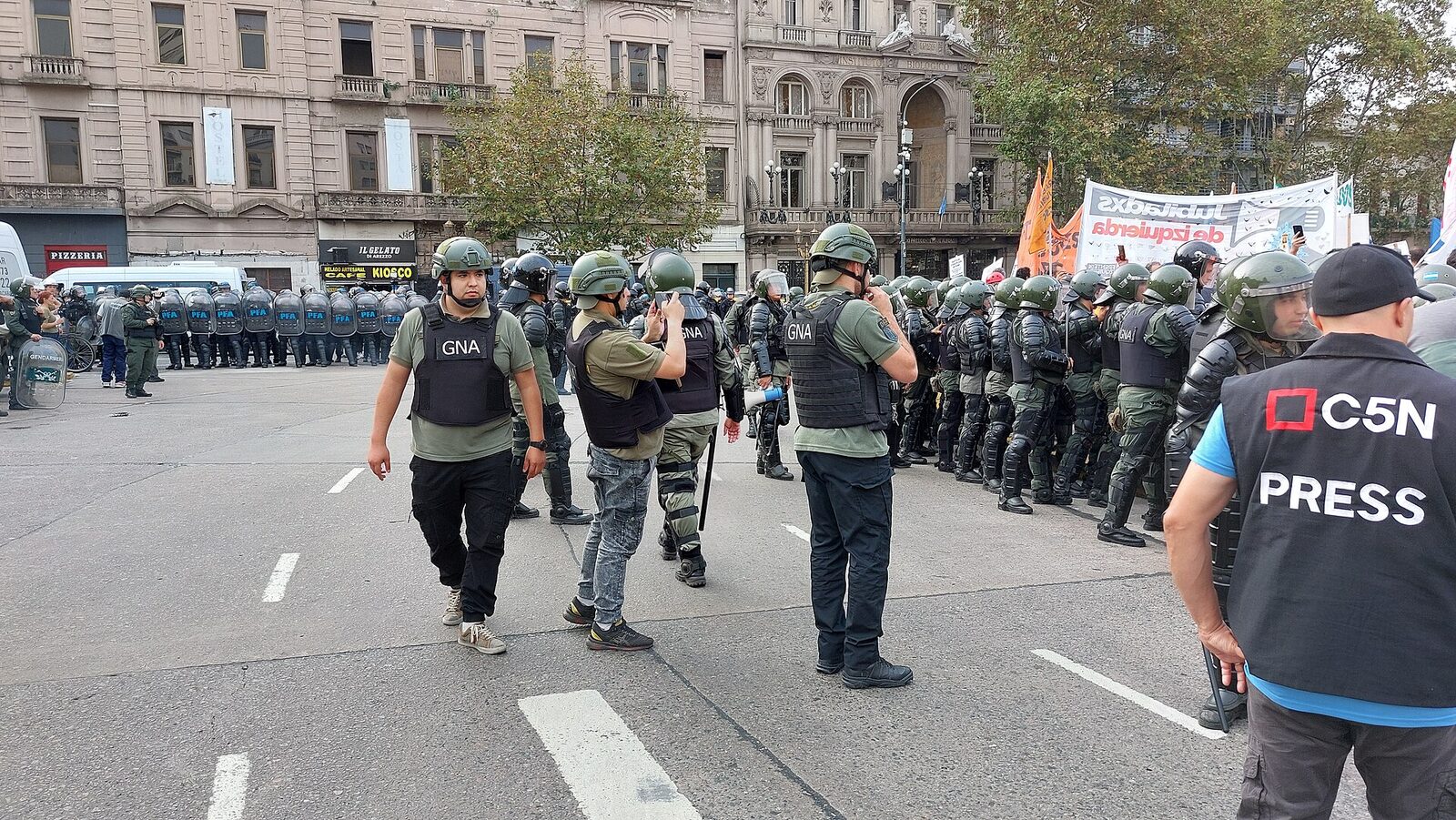 Gendarmes con chalecos filman con sus teléfonos a manifestantes frente al Congreso argentino durante una marcha de jubilados