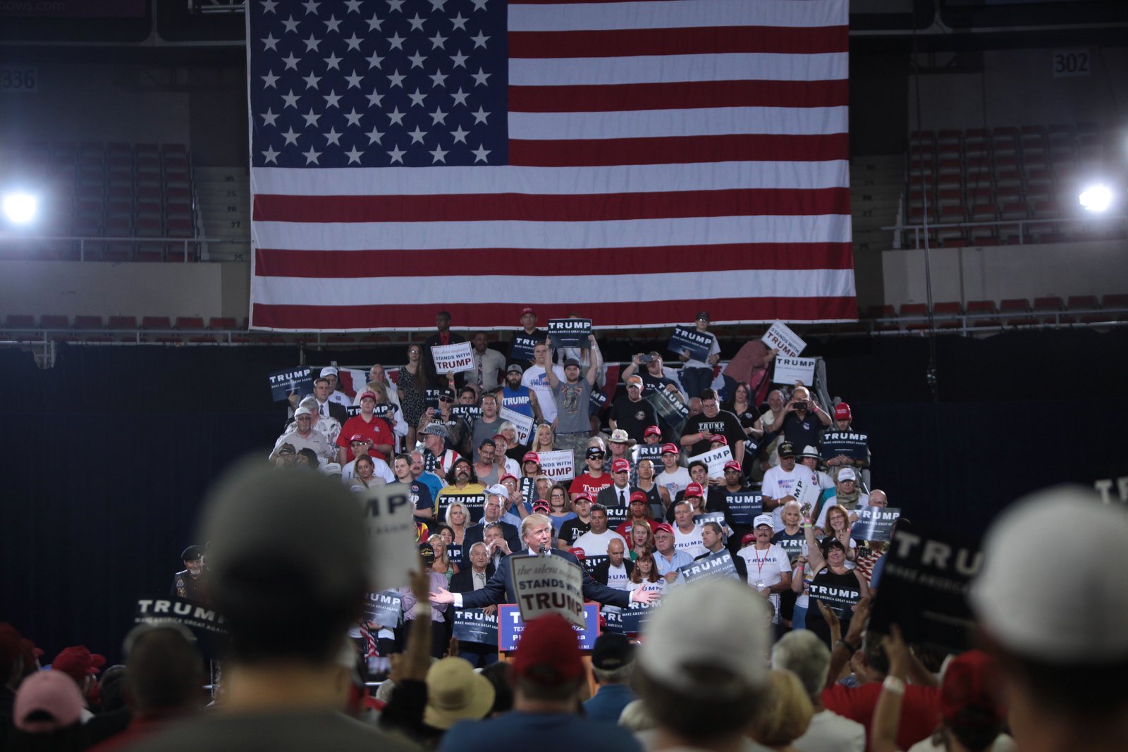 Donald Trump hablando en un acto de campana ante una multitud con carteles